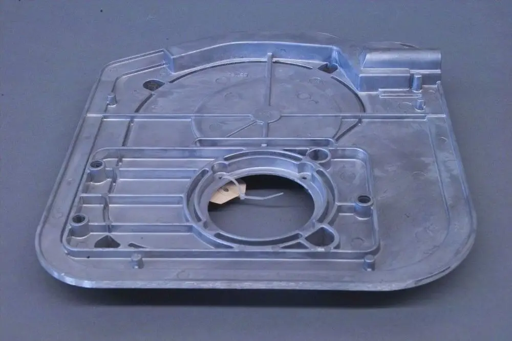 Aluminium-Grundplatte mit verschiedenen Vertiefungen und Ausschnitten, möglicherweise von Brötje, auf grauem Hintergrund.