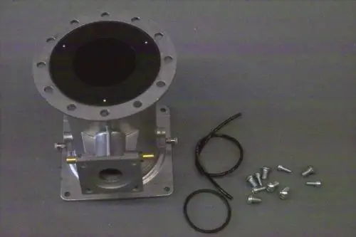 Brötje Venturi Einheit aus Metall mit ovaler Öffnung, mehreren Schrauben und Dichtungen in zerlegtem Zustand, auf grauem Untergrund dargestellt.