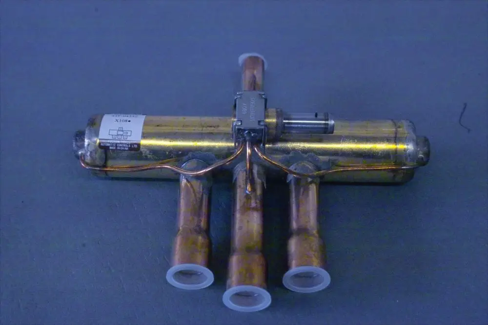 Brötje 4-Wege-Mischer mit mehreren Kupferrohren und einem Steuermechanismus, platziert auf einer grauen Oberfläche.