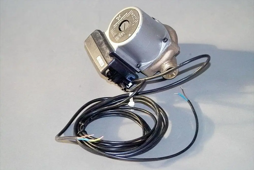 Brötje Pumpe mit silbernem Gehäuse und elektrischem Anschluss, umgeben von mehreren Kabeln. Die Pumpe ist für Trinkwarmwasseranwendungen konzipiert.
