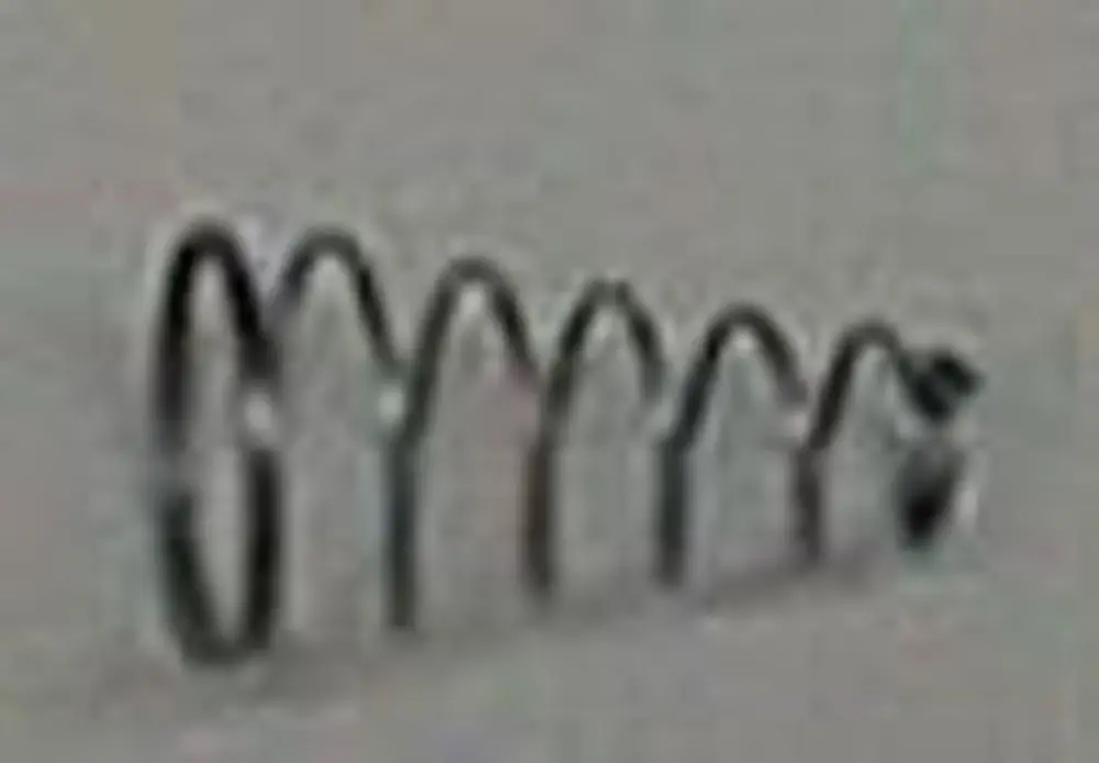 Brötje Feder in Form einer Spirale, schwarz metallisch, an einer hellen Wand montiert.