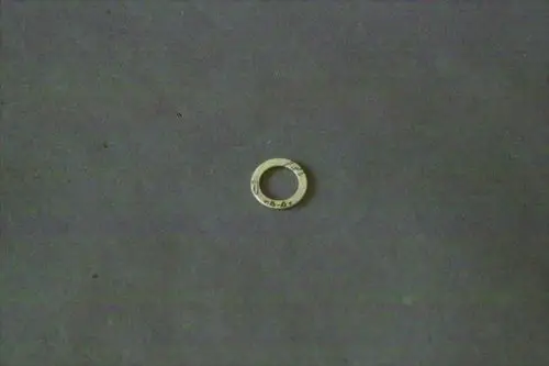 Runde Dichtung aus Metall in neutralem Farbton, mittig mit einer Öffnung, auf grauem Untergrund. Gehört zur Brötje Gasventil-Baureihe.