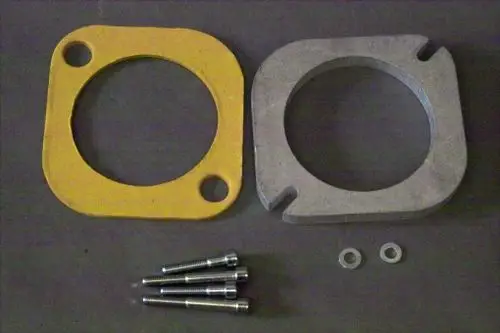 Brötje Kesselflansch aus gelbem Material und silbernem Metall, daneben mehrere Schrauben und Unterlegscheiben auf einem grauen Hintergrund.