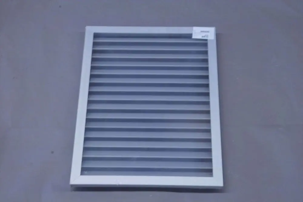 Weißes Wetterschutzgitter mit horizontalen Lamellen von Brötje auf grauem Untergrund. Das Gitter ist rechteckig und hat einen Rahmen.