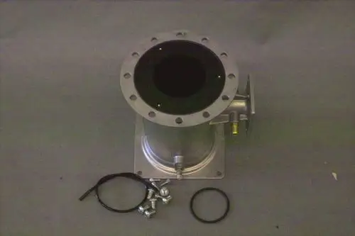 Brötje Venturi-Einheit aus Metall mit runder Öffnung oben, seitlichem Anschluss und Zubehörteilen wie Schrauben und O-Ring auf grauem Untergrund.