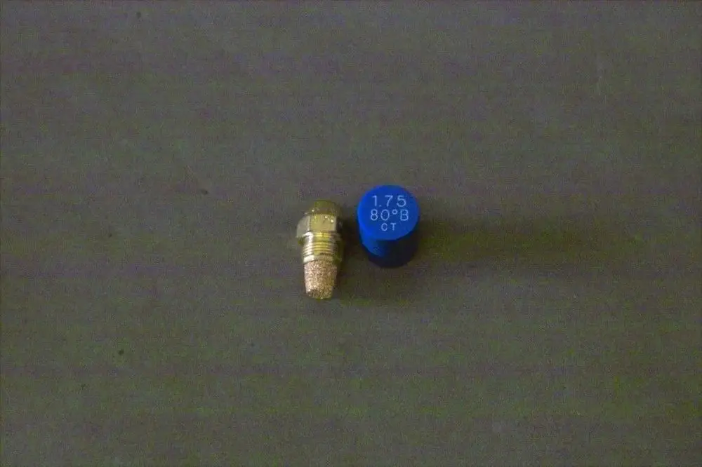 Auf dem Bild ist eine Düse von Brötje zu sehen, die eine metallische Oberfläche hat und neben einem blauen Element platziert ist.