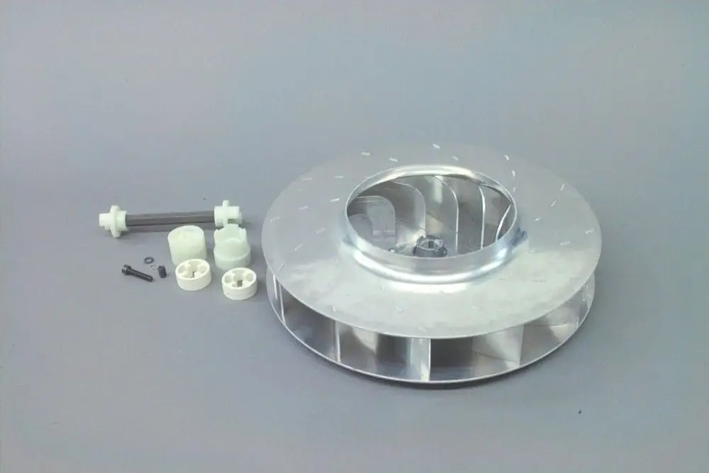 Aluminium-Gebläserad von Brötje mit zentralem Loch und mehreren Lamellen. Daneben Kunststoffteile und Schrauben für die Montage.
