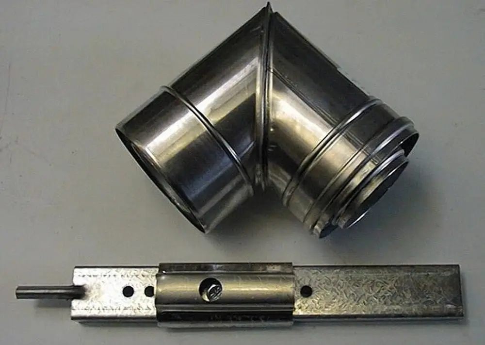Brötje Rohrbogen aus glänzendem Metall, geformt in einem 90-Grad-Winkel, liegt auf einer neutralen Oberfläche. Es zeigt eine Verbindung für Rohre oder Kanäle.