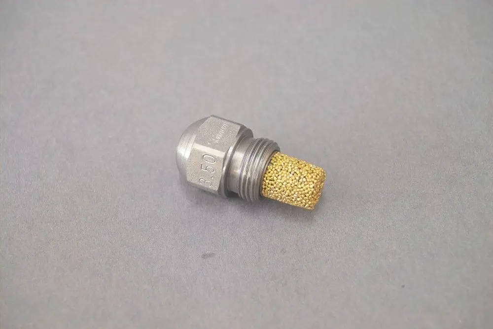 Brötje-Düse mit metallischem Gehäuse und porösem, goldfarbenem Einsatz zur Regelung von Durchfluss. Kompakt und für spezifische Anwendungen konzipiert.