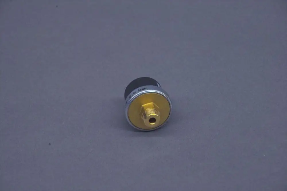Brötje Druckschalter mit einem runden Gehäuse, schwarzer Oberseite und goldfarbener Anschlussseite. Der Anschluss ist für einen Druck von 0,4 bar ausgelegt.