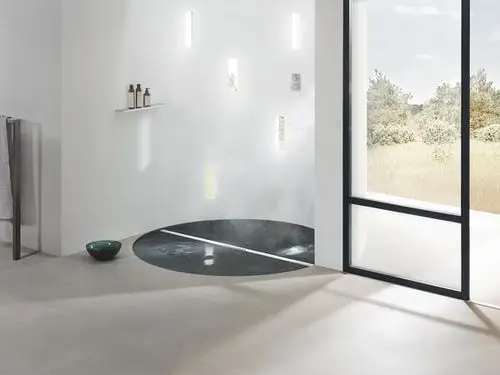 Bodenablauf von Dallmer in einem modernen Badezimmer, eingebaut in eine runde Dusche mit minimalistischem Design, umgeben von hellen Fliesen und natürlichem Licht.