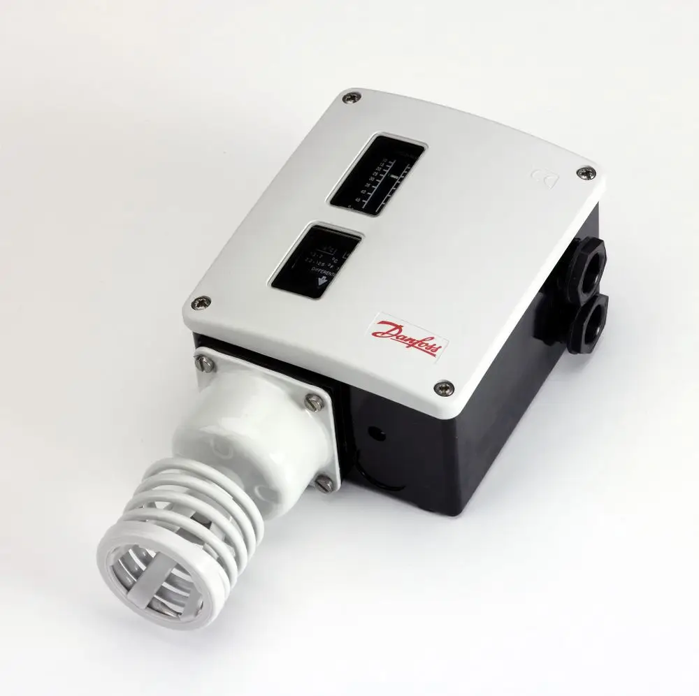 Raumthermostat von Danfoss mit zwei Anzeigeinstrumenten und einer angeschlossenen Fühlerspirale, montiert auf einer weißen Unterlage.