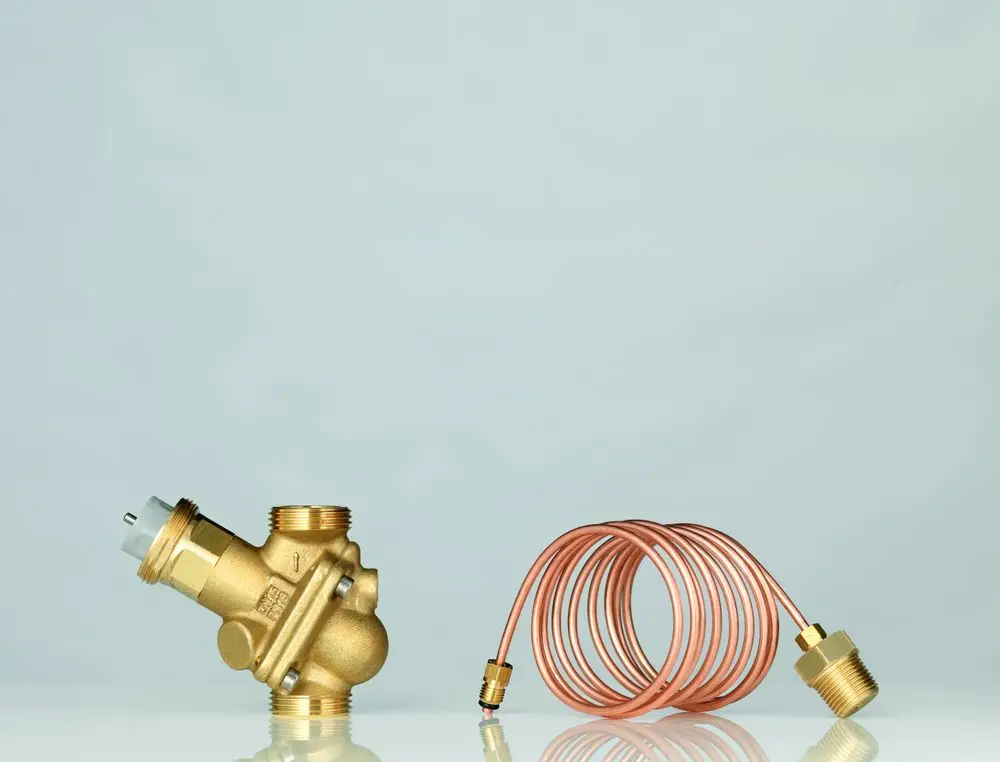 Danfoss Strangdifferenzdruckregler aus Messing mit angeschlossenem Kupferrohr, auf hellem Hintergrund, zur Regelung des Wasserflusses in Heizungsanlagen.