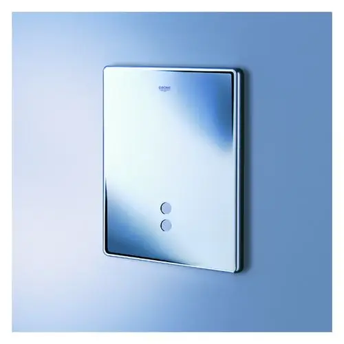 Glänzende Frontplatte von Grohe mit zwei Betätigungstasten, montiert an einer hellen Wand. Die Oberfläche reflektiert Licht und Umgebung.
