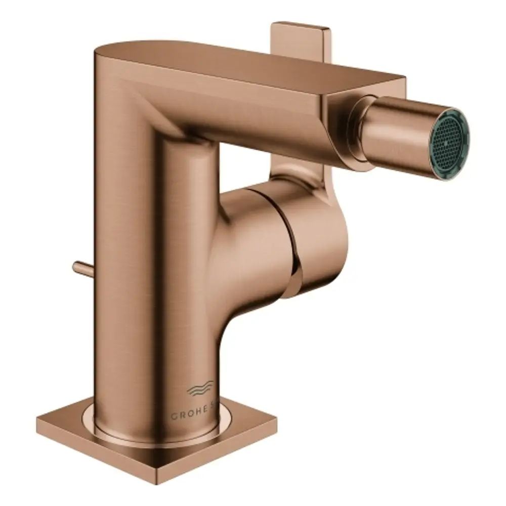 GROHE Bidetarmatur in gebürstetem Kupfer mit einem seitlichen Hebel zur Steuerung des Wasserflusses, befindet sich auf einem quadratischen Sockel.