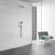 GROHE Duscharmatur mit Kopf- und Handbrause montiert an einer hellen, strukturierten Wand. Im Hintergrund ein Sitzmöbel mit einem Handtuch.