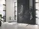 Moderne Duschsituation mit edler Grohe Handbrause, an der Wand montiert. Sicht auf transparente Duschabtrennung, fliesenverkleidete Wände und helle Fliesenunterlage.