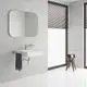 Badezimmeransicht mit weißem Waschbecken, chromfarbener Mischbatterie und Spiegel. Braune Jalousien und Holzstuhl ergänzen den Raum. Grohe-Waschtischarmatur sichtbar.