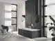 Badezimmeransicht mit freistehender Badewanne, ausgestattet mit Grohe Armaturen, an einer Wand mit dunklem Fliesenmuster und großen Fenstern für Tageslicht. Pflanzen und modernes Mobiliar ergänzen den Raum.