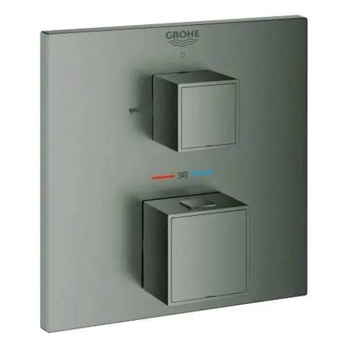 Wannenbatterie von Grohe mit zwei quadratischen Reglern zur Temperatur- und Wasserflusssteuerung, montiert auf einer Metallplatte in dunklem Farbton.