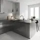 GROHE Küchenarmatur in schwarzem Finish, montiert an einer modernen grauen Küchenzeile mit einem Waschbecken und einer Arbeitsplatte aus dunklem Material. Lichtdurchfluteter Raum.
