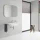 Grohe Waschtisch mit glattem Chromkörper, ausgestattet mit einer Wandarmatur, einem Spiegel über dem Waschbecken und einem kleinen Beistelltisch neben dem Waschbecken.