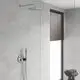 Duschbereich mit Grohe-Duschsystem, rundem Kopfbrausearm und Handbrause, Verkleidung aus hellen Wandfliesen, Glas-Trennwand und Rollladenfenster. Graue Handtücher auf einem Hocker.