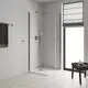 GROHE Duschbereich mit zwei klaren Glasduschtüren, einer Regendusche, Handbrause, Duscharm und einem kleinen Beistelltisch für Pflegeprodukte. Helle Wände und Holzfußboden.