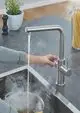 Grohe Armatur mit einem hohen Auslauf, aus Edelstahl, durch die Dampfbildung im Sichtfeld, Wasser fließt in einen Topf auf dem Herd.