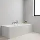 Moderne Badewanne in hellen Tönen mit Grohe Wannenbatterie an der Wand, ausgestattet mit Handbrause und seitlichen Ablagen. Helles Holzdekor auf dem Boden.