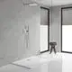 Dusche mit Grohe Armatur, Regendusche an der Decke, Handbrause an der Wand, graue Fliesen, große Fenster mit Jalousien, brauner Hocker mit Handtüchern.