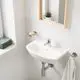 Weißes Waschbecken mit chromfarbener Armatur und abgerundeten Kanten, montiert an einer hellen Wand mit rechteckigem Spiegel und einem Handtuchhalter von Grohe.
