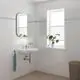 Badezimmer mit weiß gefliesten Wänden, einem modernen Waschbecken, einem wandhängenden Spiegel, einer Pflanze im Fenster und einem Handtuchhalter von Grohe an der Wand.