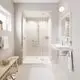 Weißes Waschbecken mit chromfarbener Wandmontage und Bedienungselementen. Grohe Armaturen sind sichtbar. Heller Raum mit modernen Fliesen und großer Dusche.
