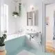 Grohe-Kollektion mit modernem Waschbecken und Chrom-Wasserhahn. Im Hintergrund ist eine Badewanne sowie Pflanzen und ein Spiegel sichtbar. Helle Fliesen in Aqua-Farbe.