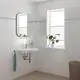 Badezimmer mit weißem Wand- und Bodenfliesen, Waschbecken mit Grohe Armatur, runder Spiegel, Fenster mit Pflanzen und Handtuchhalter.