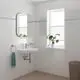 Weißes Waschbecken mit chromfarbener Mischbatterie von Grohe, Wandmontage, daneben ein Handtuchhalter mit blauem Handtuch. Fenster mit Pflanzen im Hintergrund.