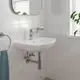 Weißes Waschbecken mit einem modernen, hochglänzenden Grohe-Wasserhahn und einer Seifenschale. Weiße Fliesen an der Wand und ein Handtuchhalter sind sichtbar.