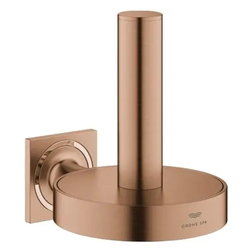 Kreuzförmiger, gebürsteter Halter für Toilettenpapier in Warm Sunset-Finish von Grohe. Montiert an einer quadratischen Wandplatte.