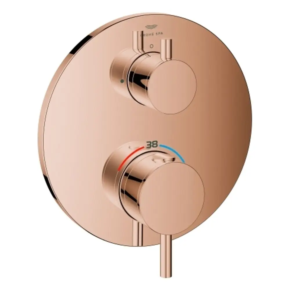 Grohe Brausebatterie in Roségold mit zwei Drehreglern zur Temperatureinstellung und Ausflusskontrolle, montiert auf einer runden Plattenoberfläche.