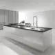 Grohe Armatur mit Profibrause, montiert an einer modernen Kücheninsel mit schwarzer Arbeitsplatte und weißen Schränken, helle Umgebung mit Bodenfliesen.