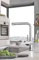 Küchenarmatur mit ausziehbarer Brause von Grohe. Verchromtes Finish, modernes Design, installiert am Spülbecken mit frischem Gemüse im Vordergrund.