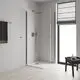 Badezimmer mit moderner Duschkabine, Glaswänden und Grohe Kopfbrause an Wandmontage, hellen Wänden und Fenster. Ein Tisch mit Pflegeprodukten ist sichtbar.