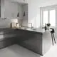 Moderne Küche mit glänzenden, grauen Oberflächen, einer Edelstahlspüle und einem Wasserhahn von Grohe, daneben eine Holzplatte mit Obst und einem kleinen Pflanzenarrangement.