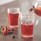 GROHE Teegläser mit dampfendem Getränk, zwei Gläser im Vordergrund, frische Himbeeren und Heidelbeeren im Vordergrund auf einer Tischoberfläche.