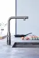 Hochwertige Küchenarmatur von Grohe mit ausziehbarem Auslauf in einer matten, dunklen Oberfläche. Im Hintergrund sind ein Pfannen und Eier auf der Arbeitsfläche sichtbar.