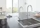 Zweigriff-Armatur von Grohe mit zwei Ausläufen in verchromtem Finish. Die Armatur ist in einem modernen Küchenumfeld auf einer grauen Arbeitsplatte abgebildet.