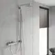 Einfache Duscharmatur von Grohe mit an einer Wand montierter Hand- und Kopfbrause. Dunkle Jalousien und ein Handtuchhalter sind im Hintergrund sichtbar.