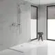 Grohe Duschsystem mit einer Wandmontage, bestehend aus einer Kopf- und Handbrause sowie einer Steuerungseinheit, in einem modernen Badezimmer mit weißen Fliesen und großen Fenstern.