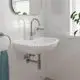 Chromene Waschtischbatterie von Grohe mit einem geschwungenen Auslauf, installiert an einem weißen Waschbecken in einem modernen Badezimmer mit heller Fliesenwand.